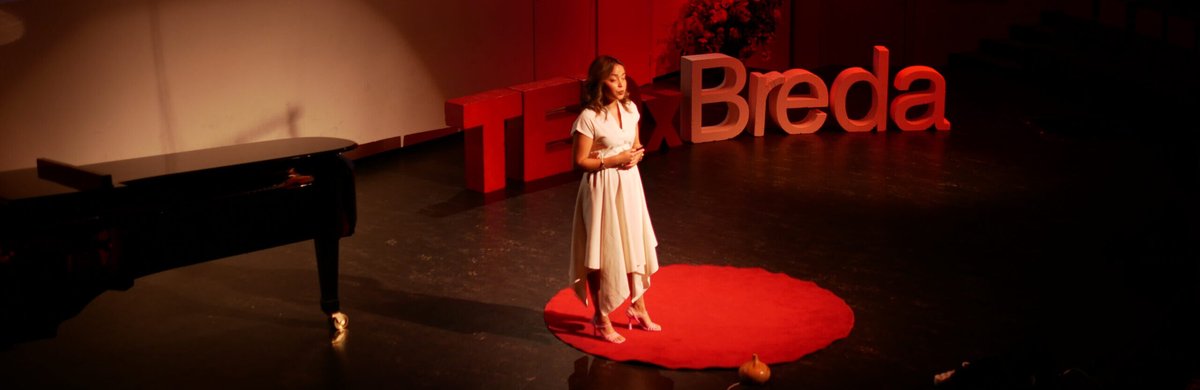Dame op rood podium voor de letters TEDxBreda